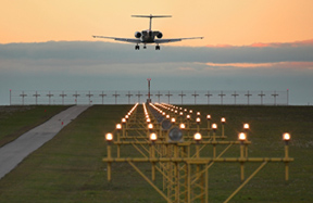 Photo of an airplane just before landing. Runway lights can be seen in the foreground.